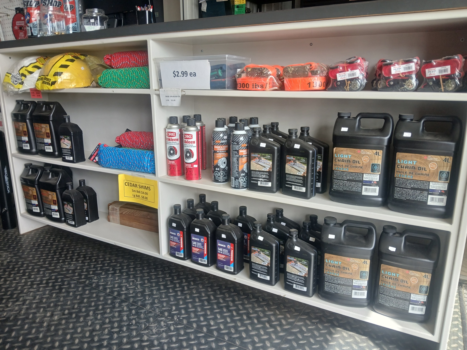 Shop shelves stocked with chain oil, motor oil, ratchet straps, rope and hard hats